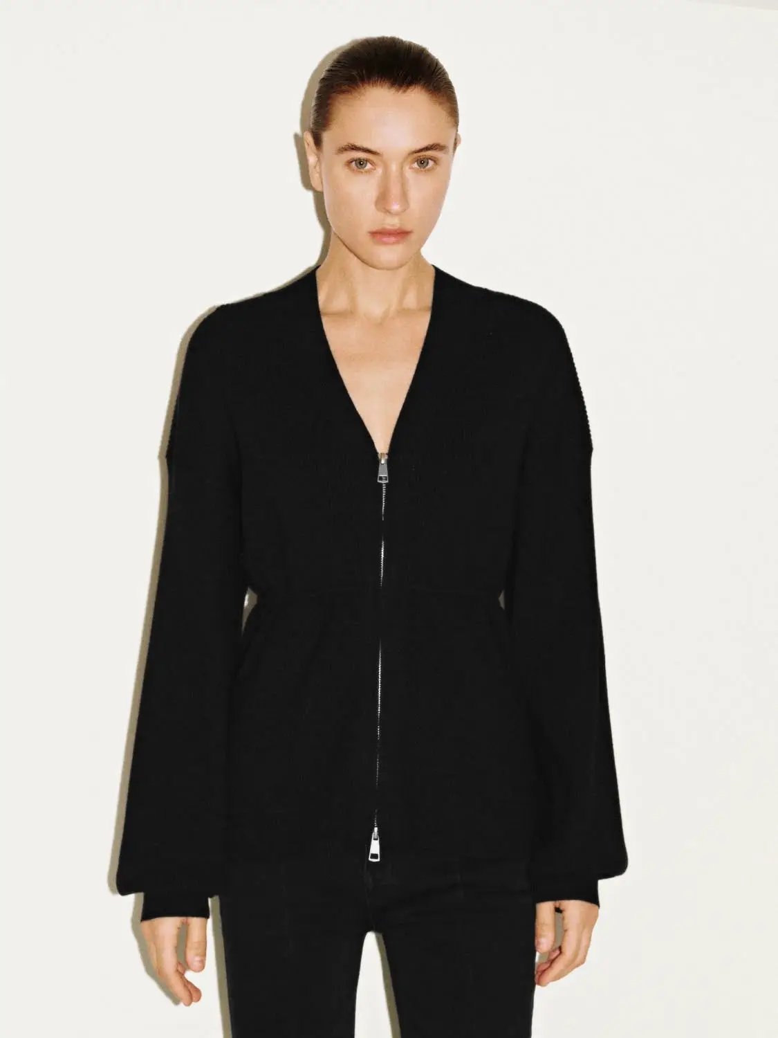 Women's zip-up knitted cardigan with balloon sleeves in black.