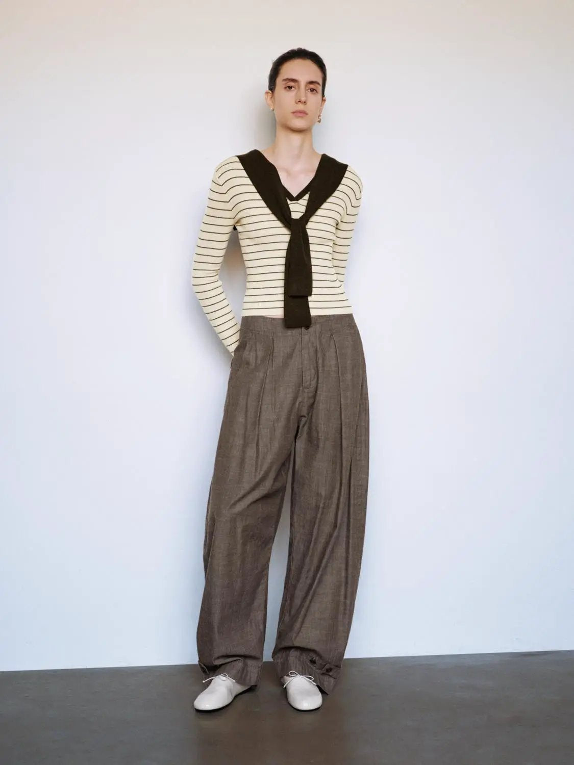 Striped shawl-knit fitted V-neck long-sleeve T-shirt in cream with black stripes, paired with brown wide-leg trousers.