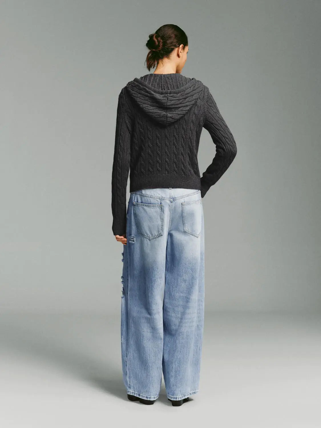 Knit jacket with dark gray cable-knit hood, back view on model in light denim jeans