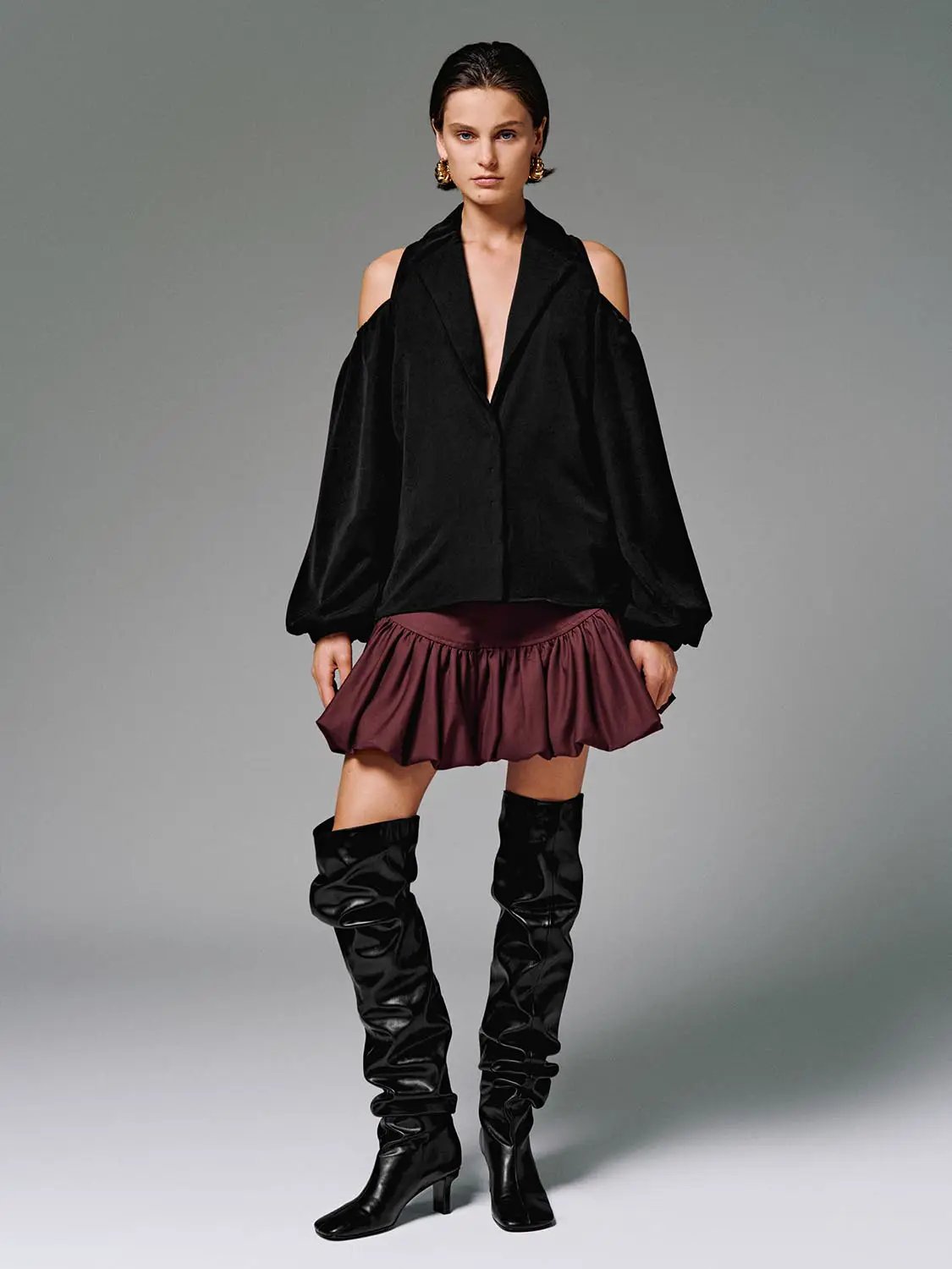 Cotton tiered ruffle skirt in burgundy worn with a black off-shoulder top and knee-high boots