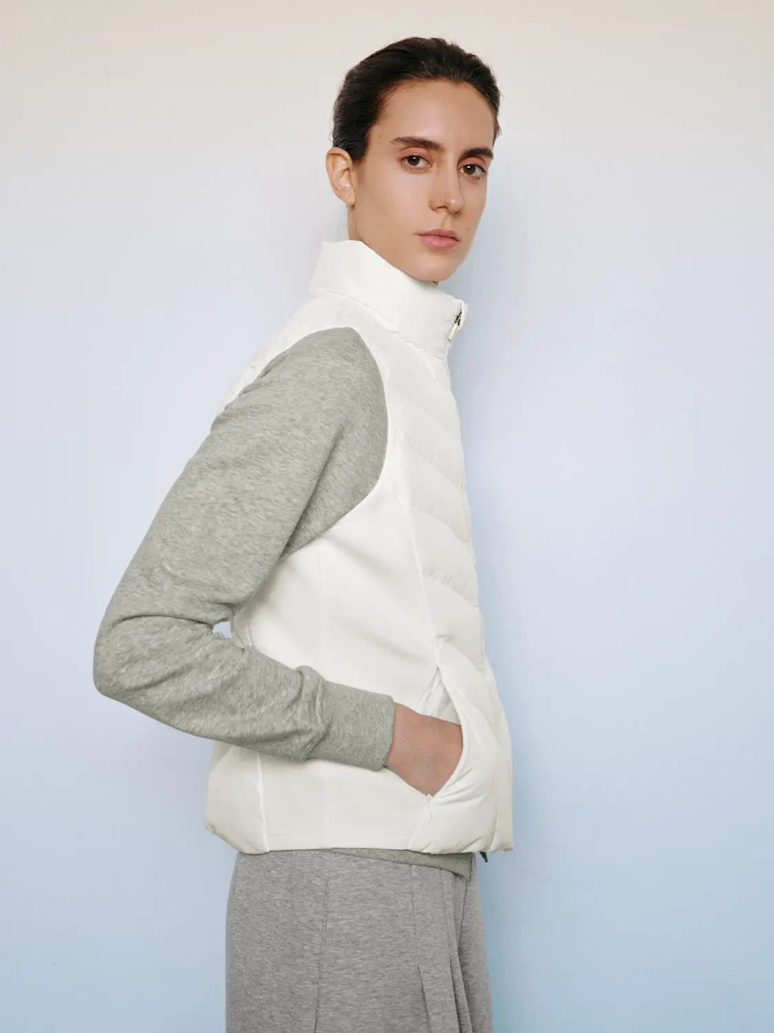 Down jacket white quilted puffer vest layered over a gray sweatshirt.