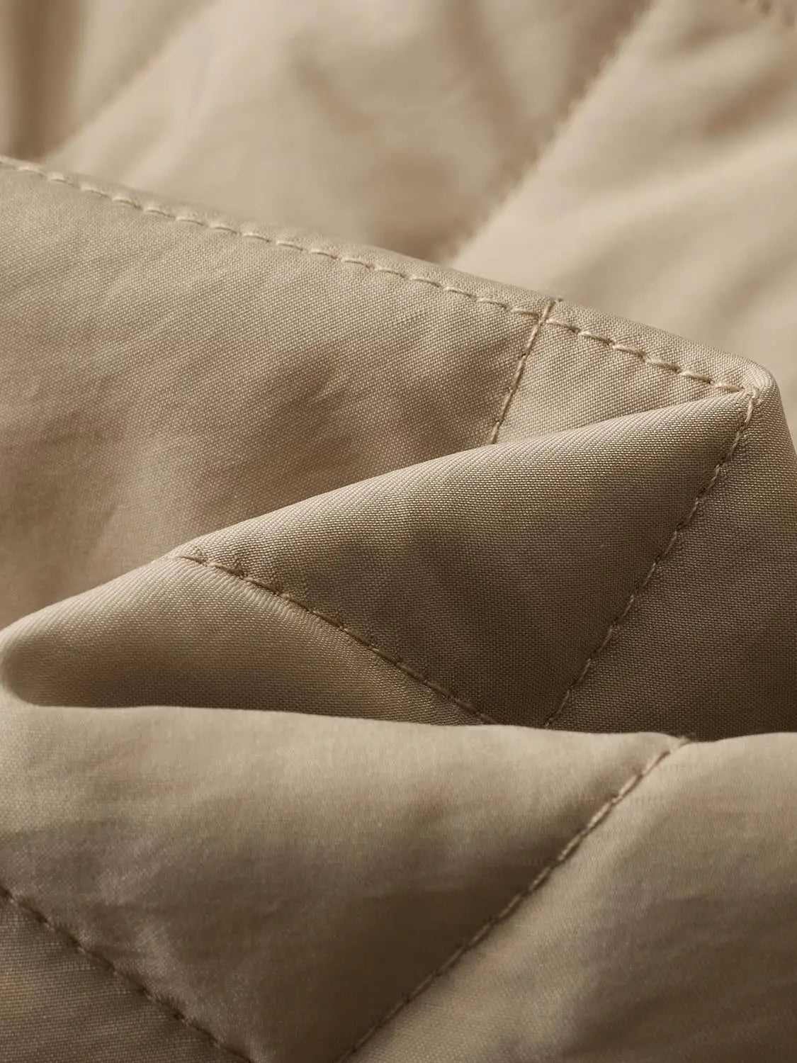 Padded jacket in beige fabric with visible stitching and seam details.