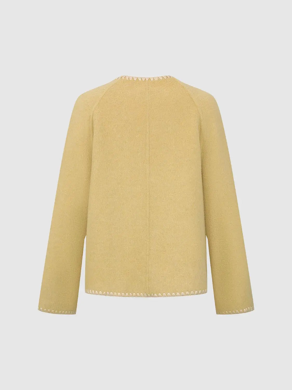 Coat in pale yellow with white zigzag stitching along hem, back view