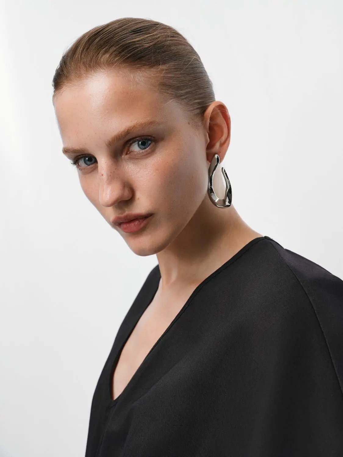 V-neck black cotton-linen blend blouse worn by model, simple silhouette.
