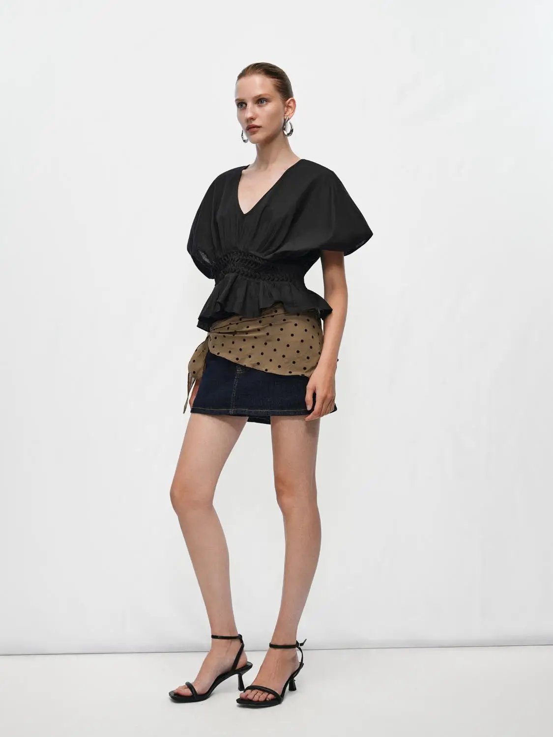 V-neck puff-sleeve blouse in black cotton-linen blend with smocked waist, peplum hem and draped silhouette