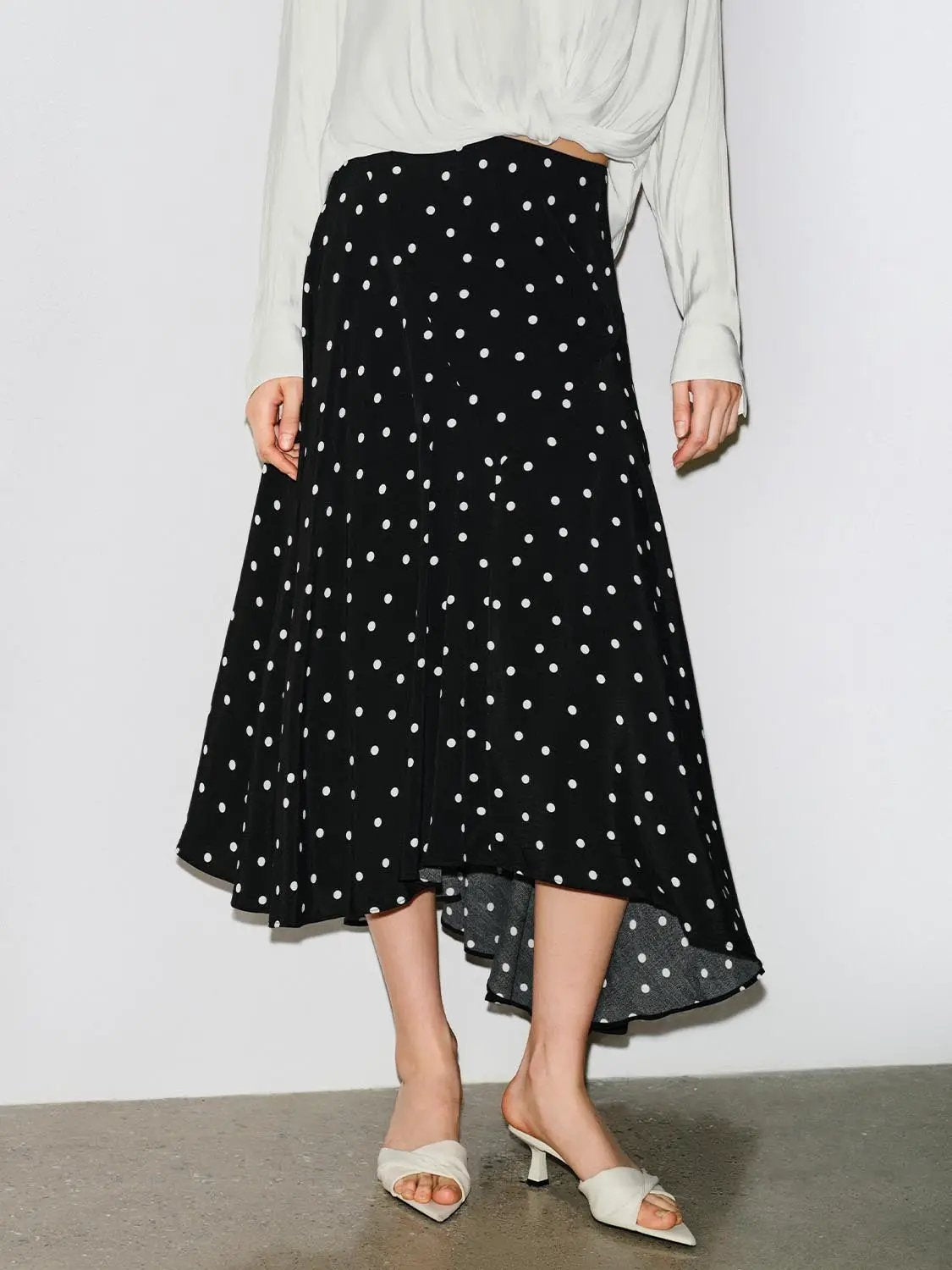 Polka dot asymmetric-hem maxi wrap skirt in black with white polka dots.
