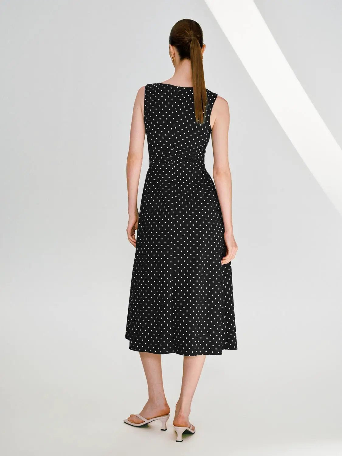 Polka dot knit sleeveless A-line dress in black with white dots, flattering fit, back view
