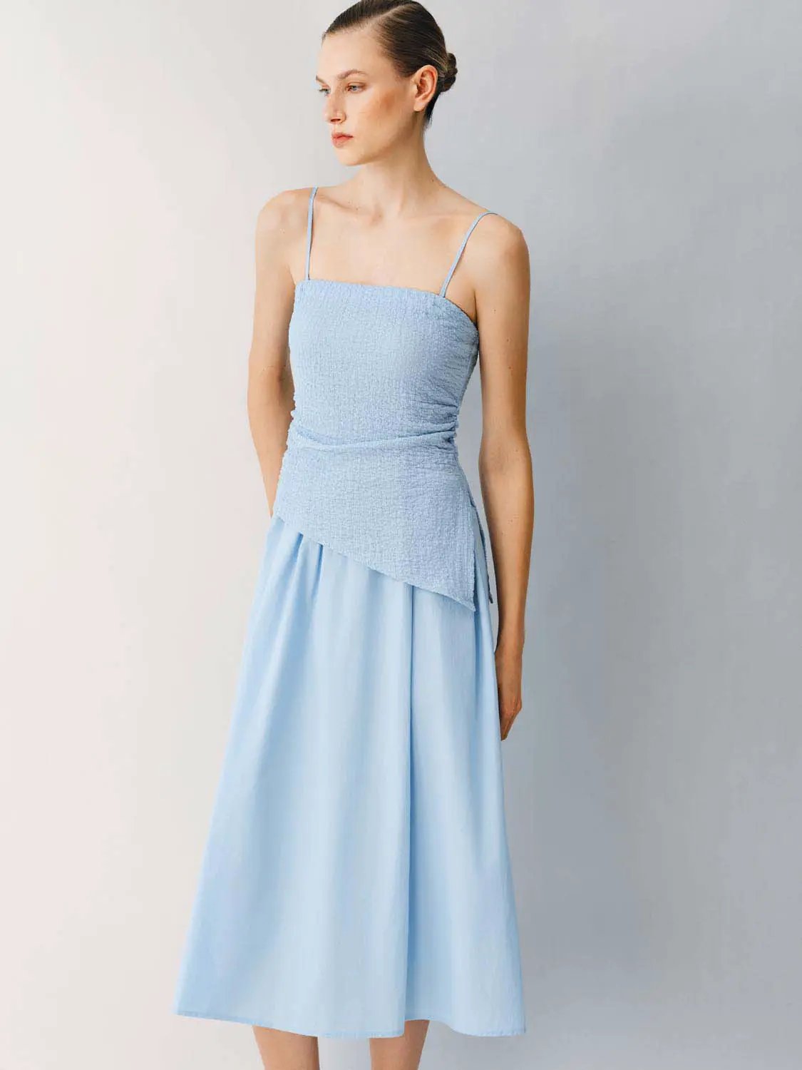 Thin stretch fabric spaghetti-strap A-line midi dress in light blue with smocked bodice and asymmetric peplum overlay