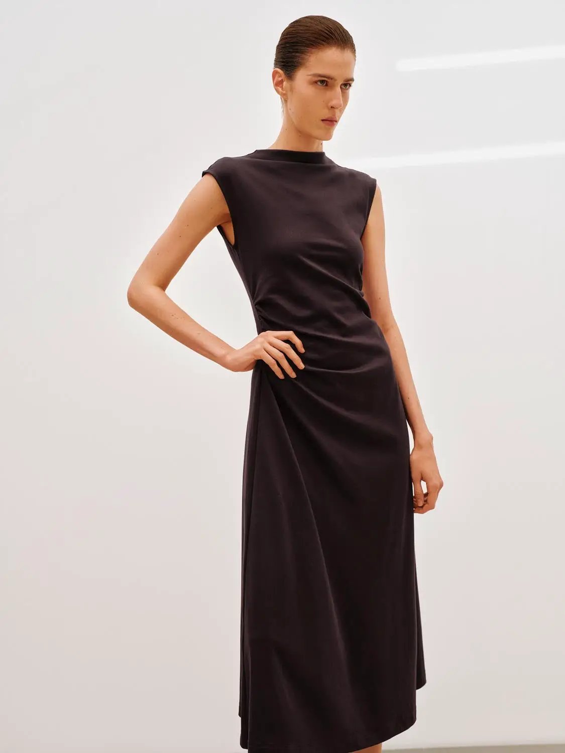 A-Line dress in dark color, sleeveless, knee-length with subtle waist drape.