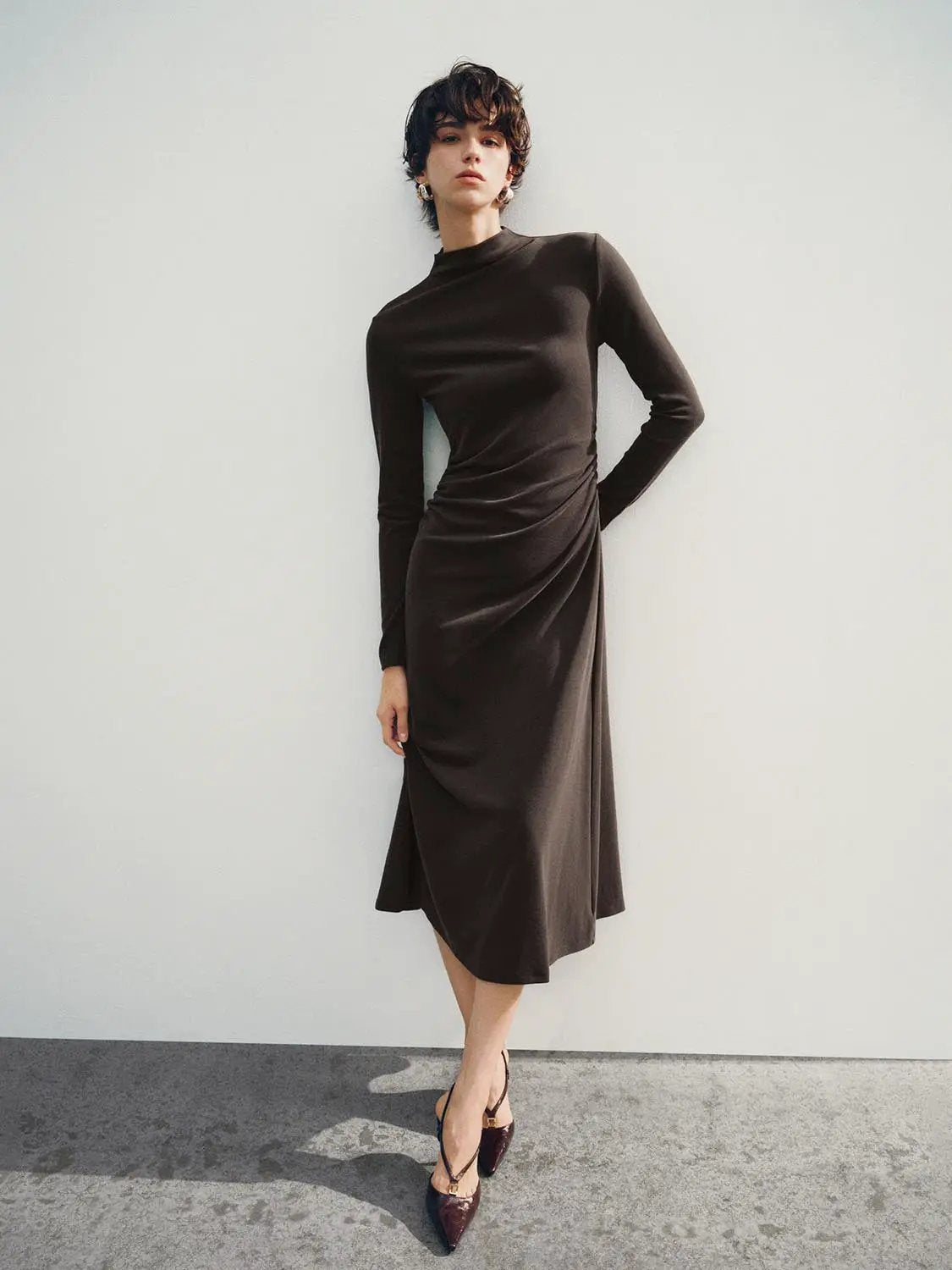 A-line dress in chocolate brown with long sleeves and waist drape, knee-length.