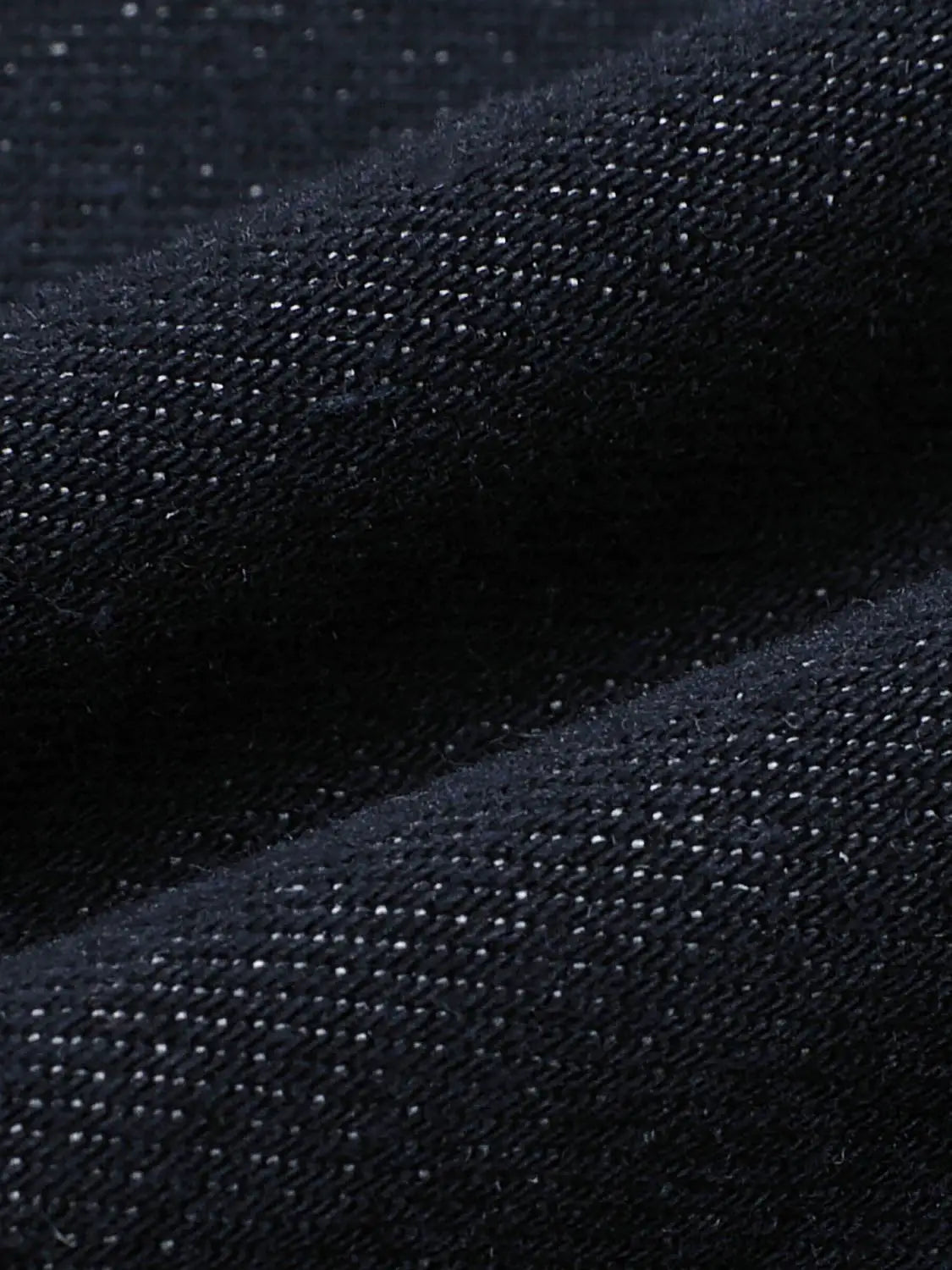 Jeans denim close-up in dark indigo with visible weave texture