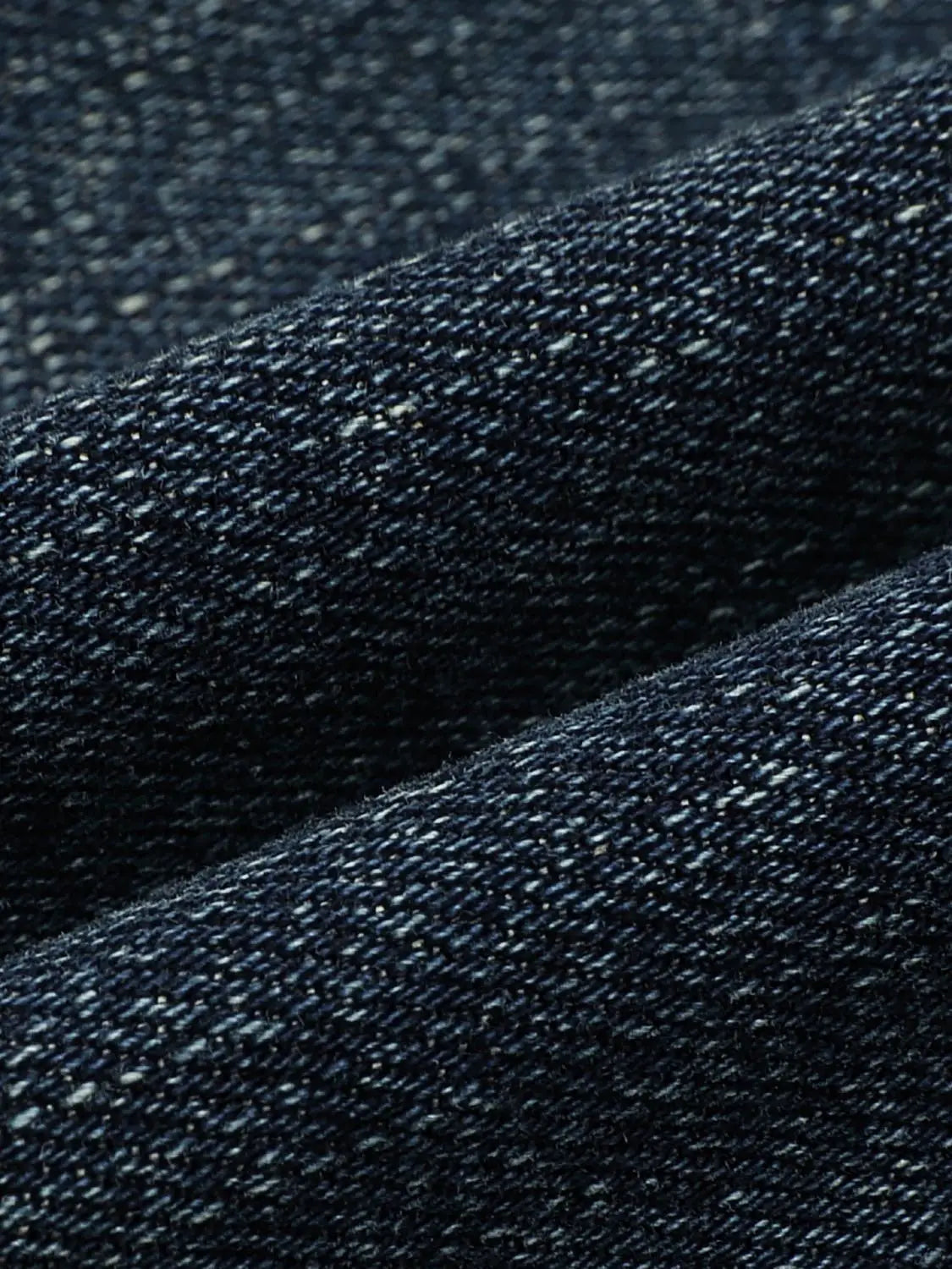 Jeans close-up in dark indigo denim fabric with textured weave