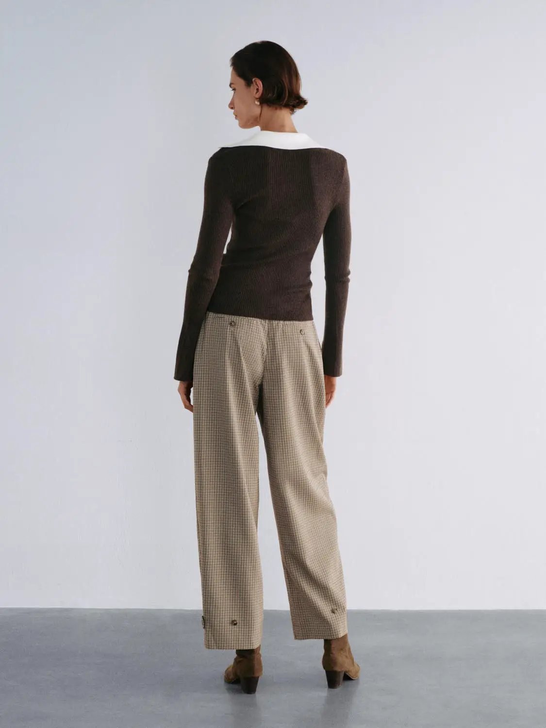 Knitted cardigan in dark brown ribbed knit; white collar peeks with beige plaid trousers and brown ankle boots (3-piece)