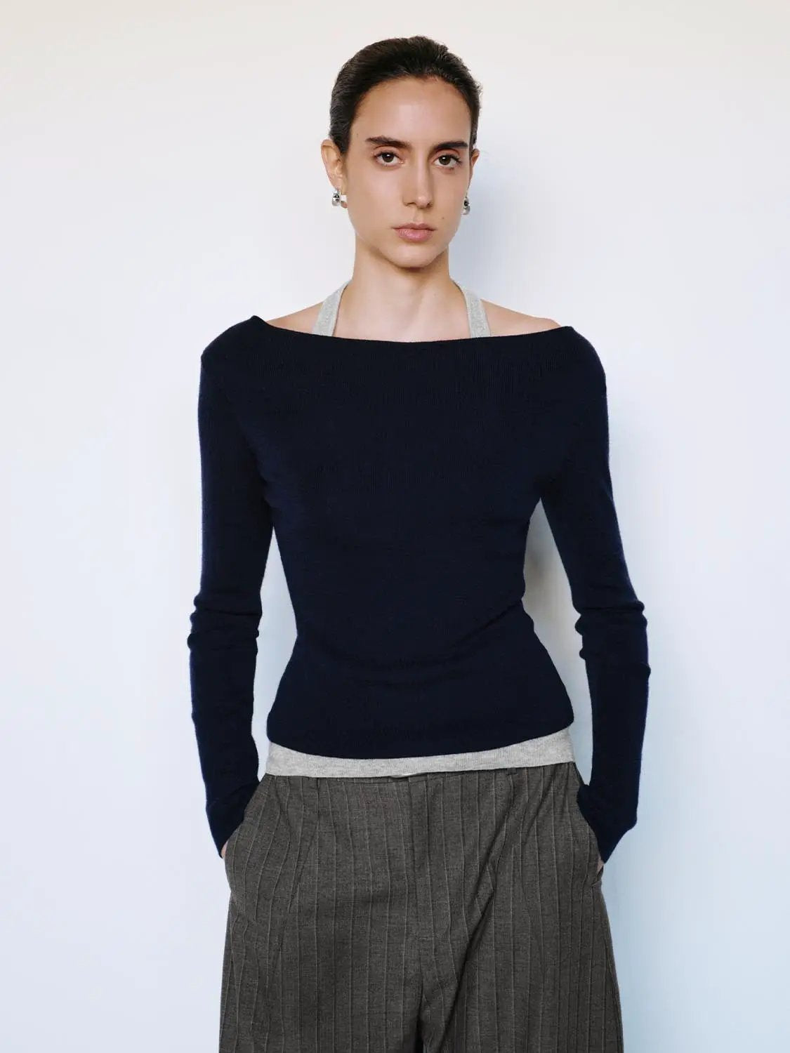 Fitted navy boat-neck knit top with long sleeves and light gray contrast hem.