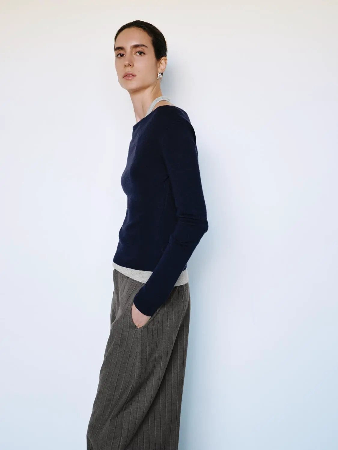 Fitted navy knit top with boat neck, long sleeves, and light gray contrast hem