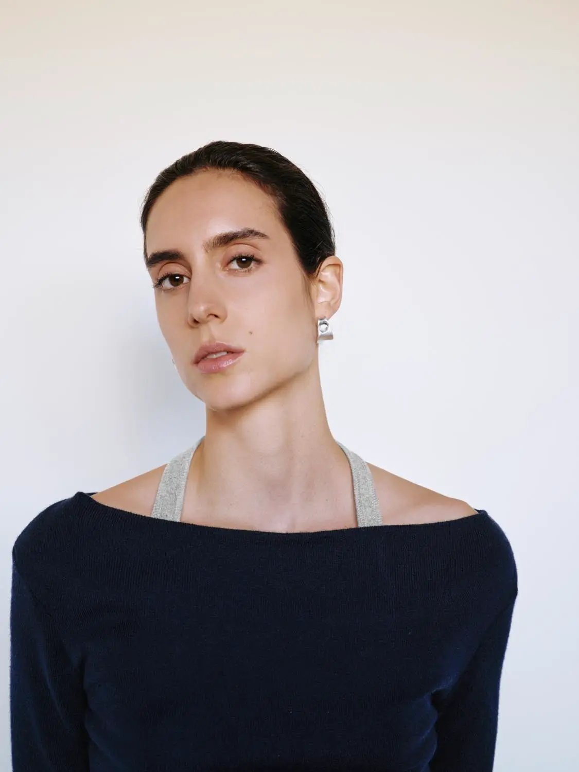 Fitted navy knit boat-neck long-sleeve top with light gray shoulder strap.
