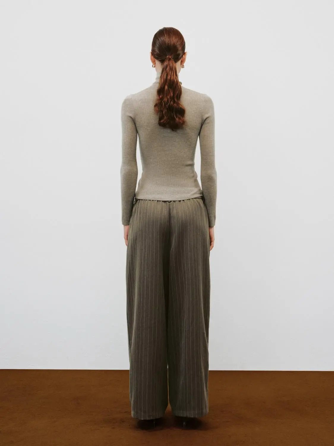 Beige ribbed knit cardigan with mock neck, long sleeves; back view with wide-leg pinstripe trousers.