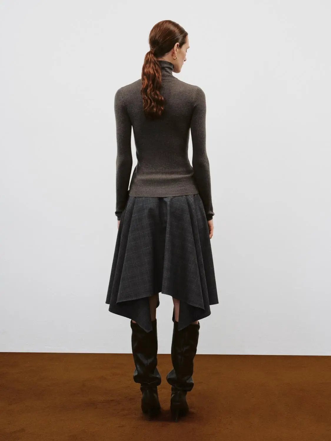 Ribbed slim mock-neck knit cardigan in dark gray, back view on model with a plaid skirt and knee-high boots.