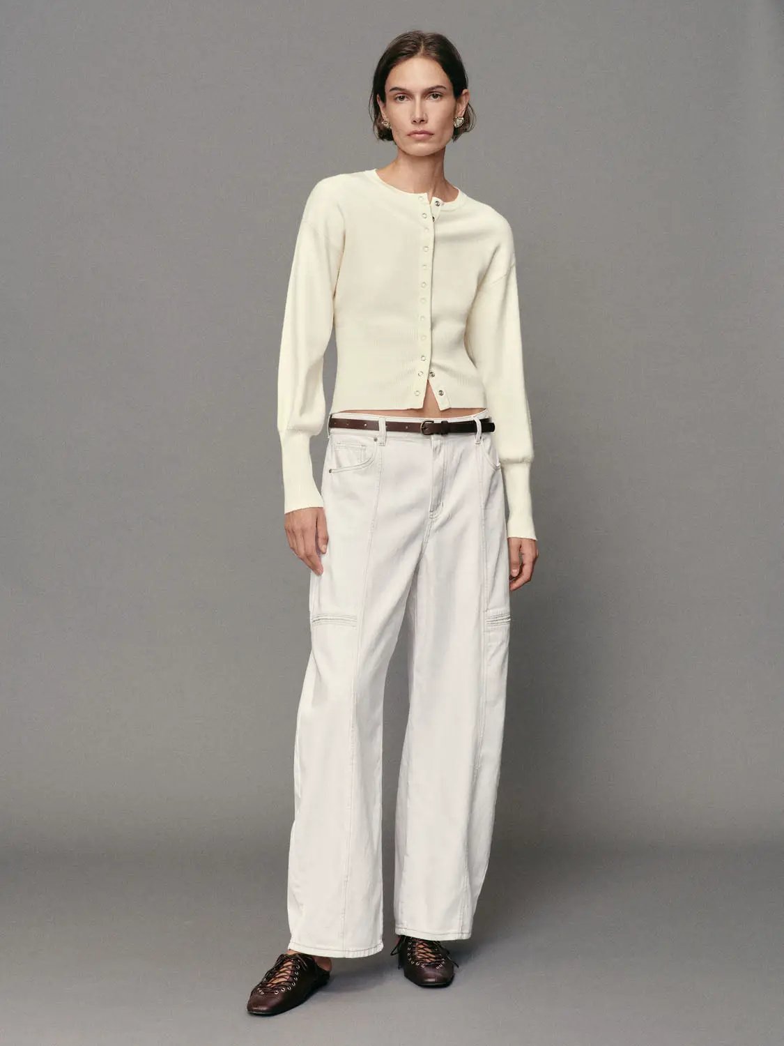 Ribbed button-front crew-neck long-sleeve cardigan, cream knit, styled with white jeans and brown belt.