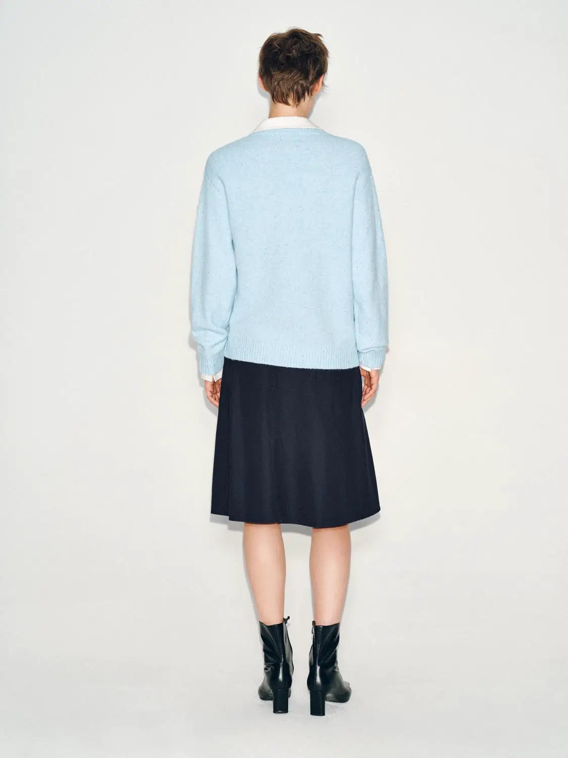 Knit T-Shirt back view in light blue knitted fabric; model wears navy skirt and black ankle boots