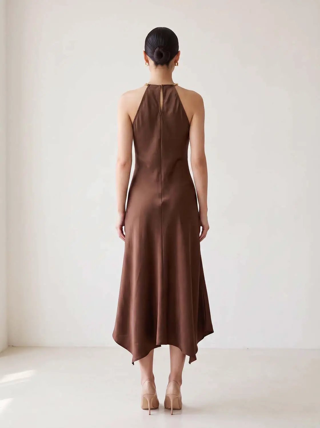 A-line satin dress in brown with halter neckline and asymmetric hem, back view.