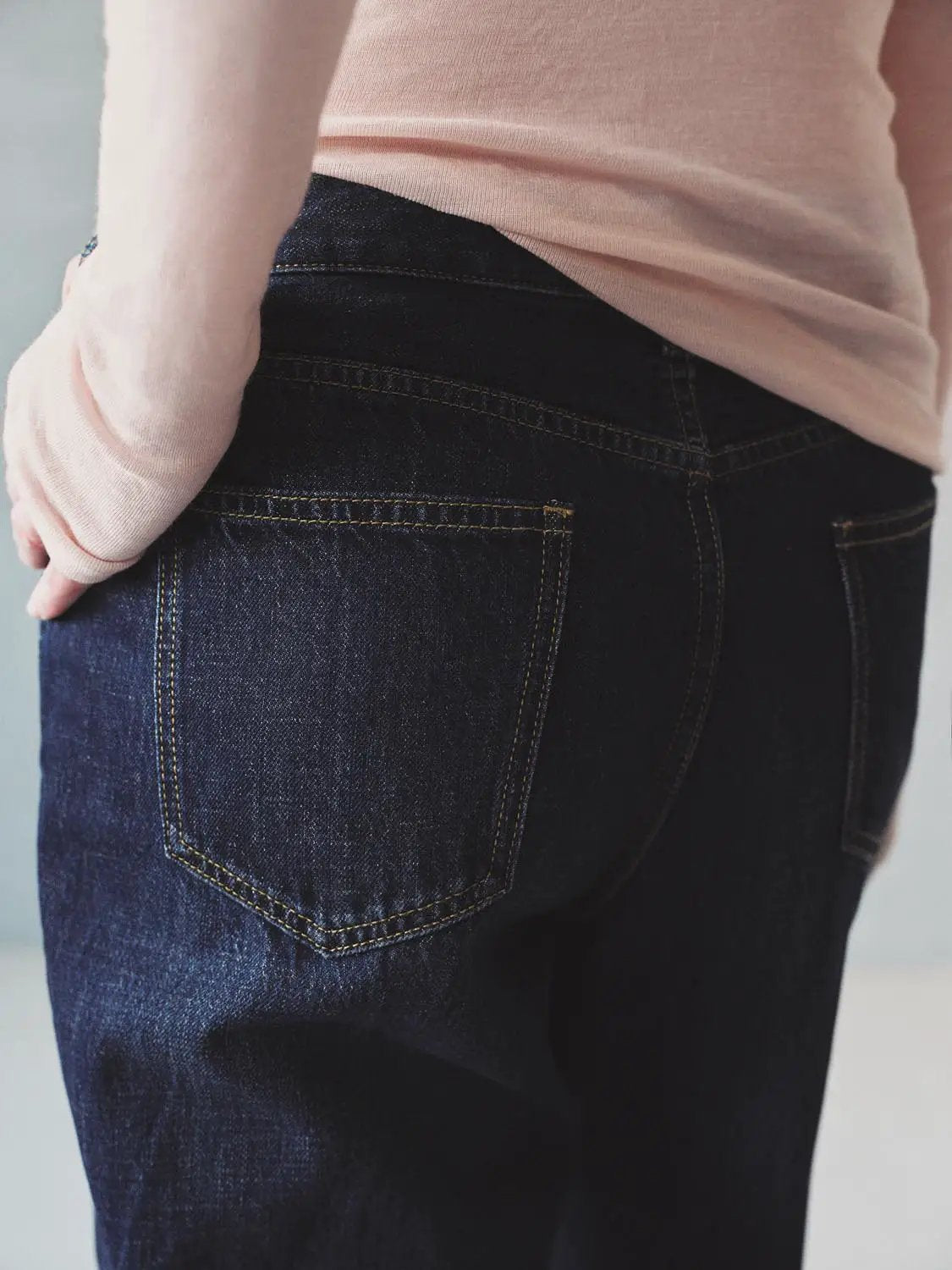 Jeans in dark indigo denim with yellow contrast stitching and back pockets.