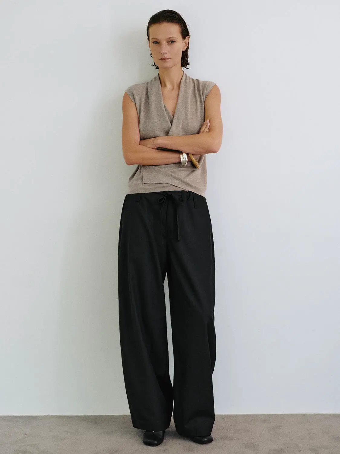 Sleeveless wrap-front knit top with collar in taupe, paired with black wide-leg pants.
