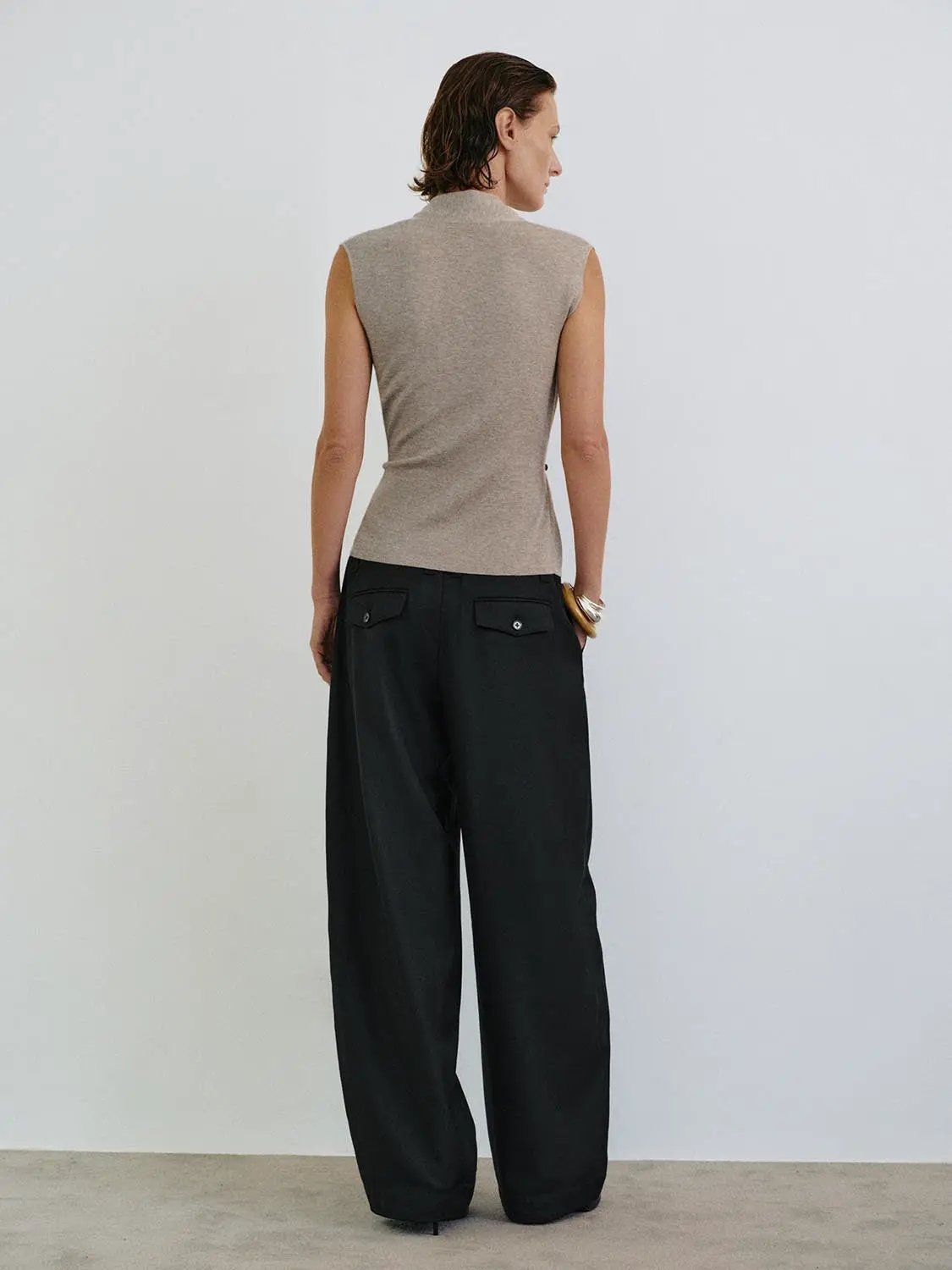 Sleeveless wrap-front knit top with collar in beige by Urban Revivo Fashion; paired with black wide-leg trousers.