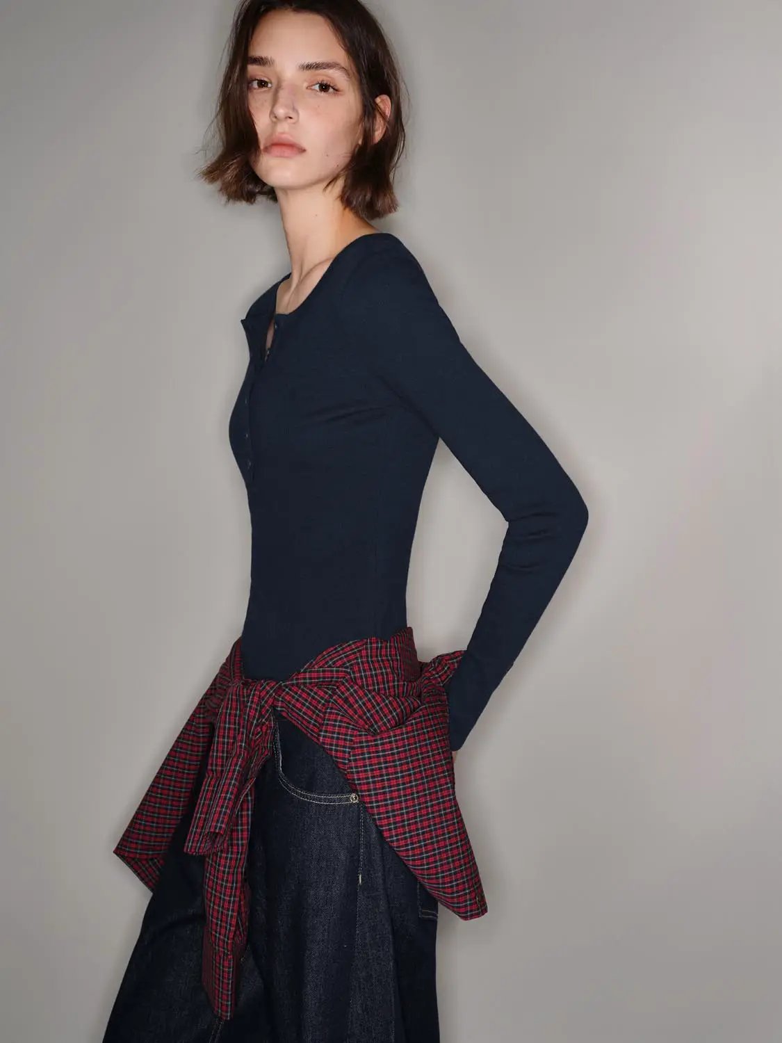 T-Shirt, navy long-sleeve with button placket; model wears red plaid shirt tied at waist over dark denim.