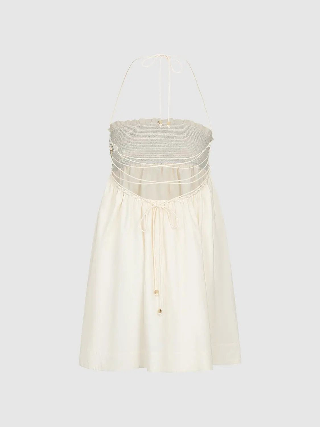 A-line dress in ivory with halter neck, smocked bodice and waist ties.