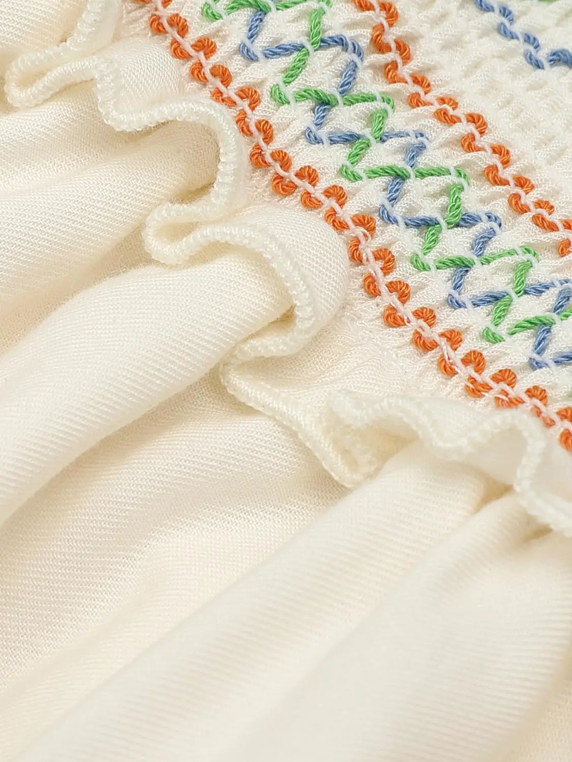 A-Line Dress ivory satin with colorful embroidered trim in orange, blue and green along a ruffled edge.