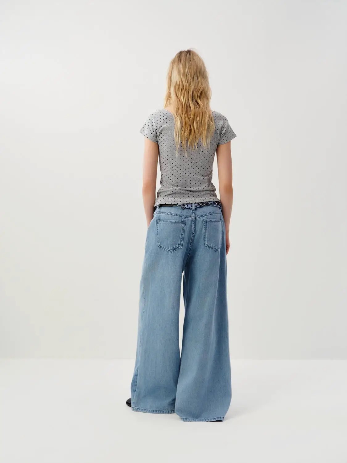 Wide-leg cotton jeans with decorative patch detail in light-wash blue denim, back view.