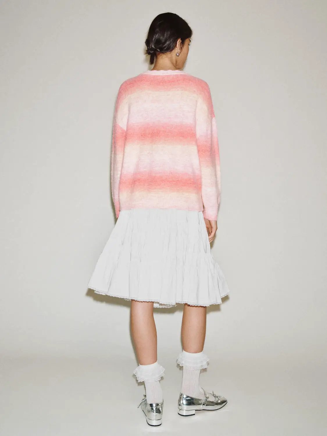 Knitted T-Shirt pink gradient stripes, back view; paired with a white pleated skirt