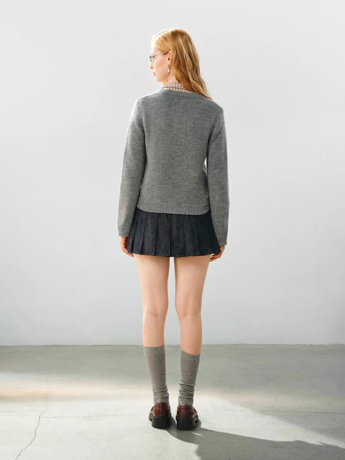 Grey knitted cardigan back view; long sleeves and ribbed hem.