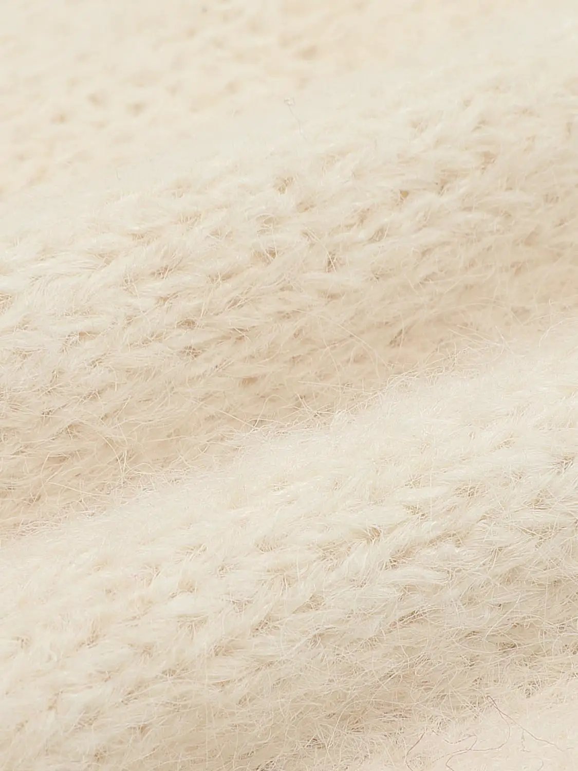 Cream knit cardigan fabric close-up with soft fluffy texture