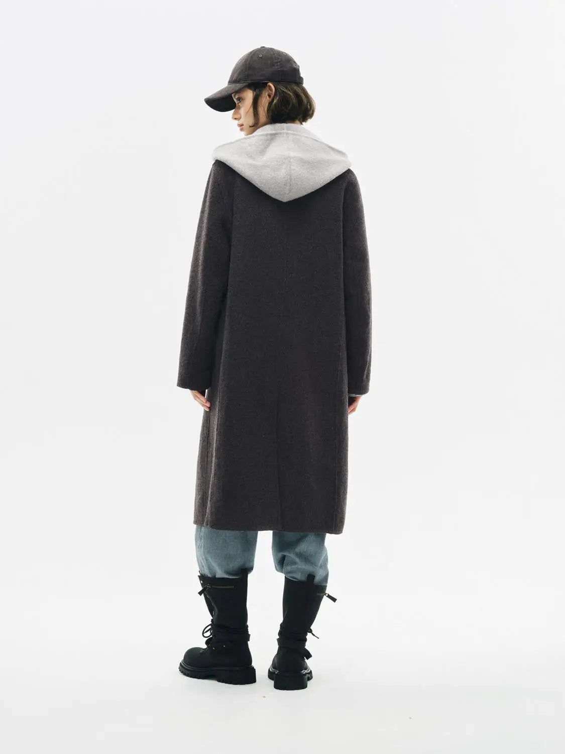 Coat, long dark gray wool with light gray hood, back view of model wearing blue jeans and black boots