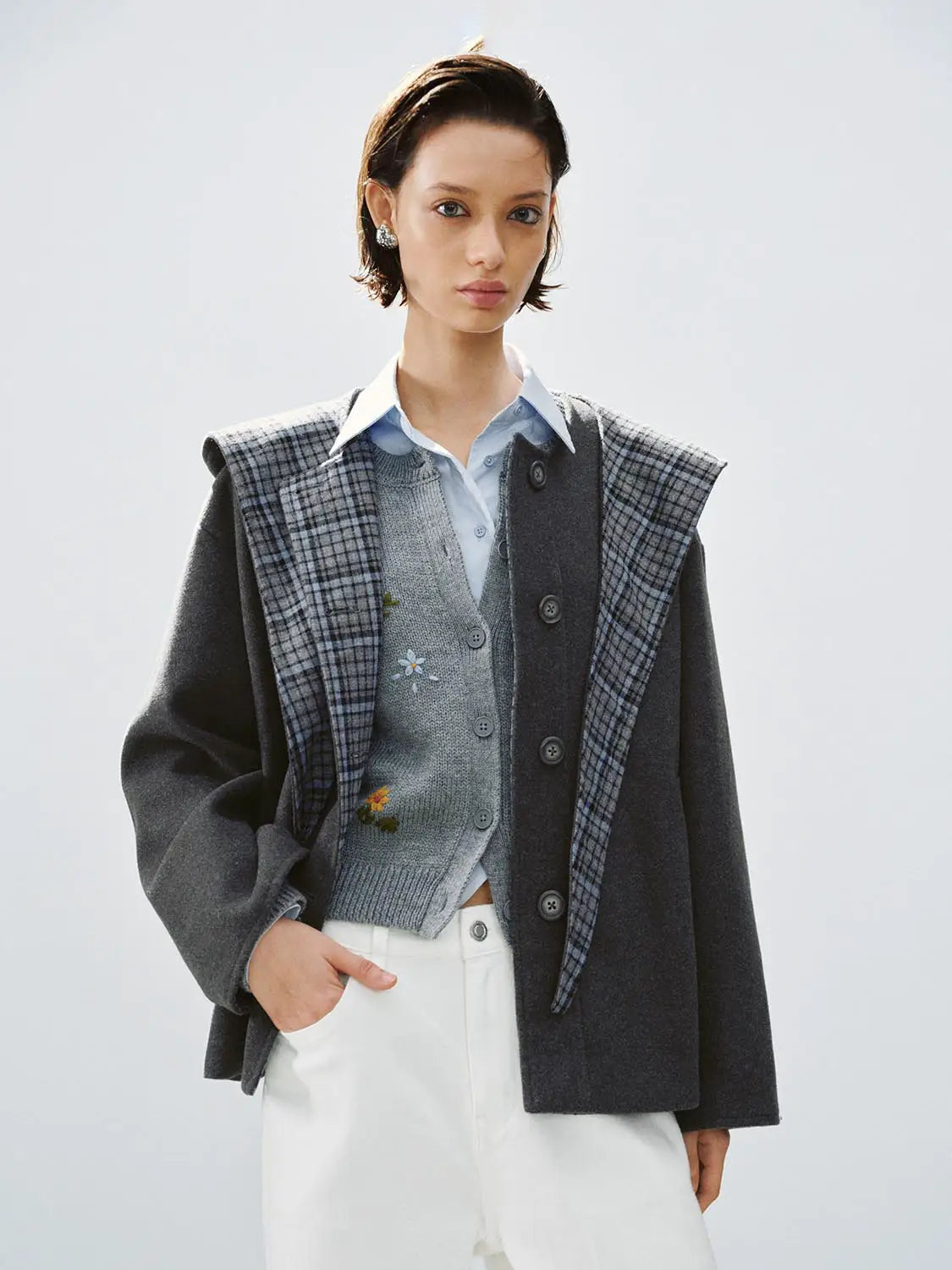 Coat, oversized dark gray wool with plaid panel, layered over a light blue shirt.
