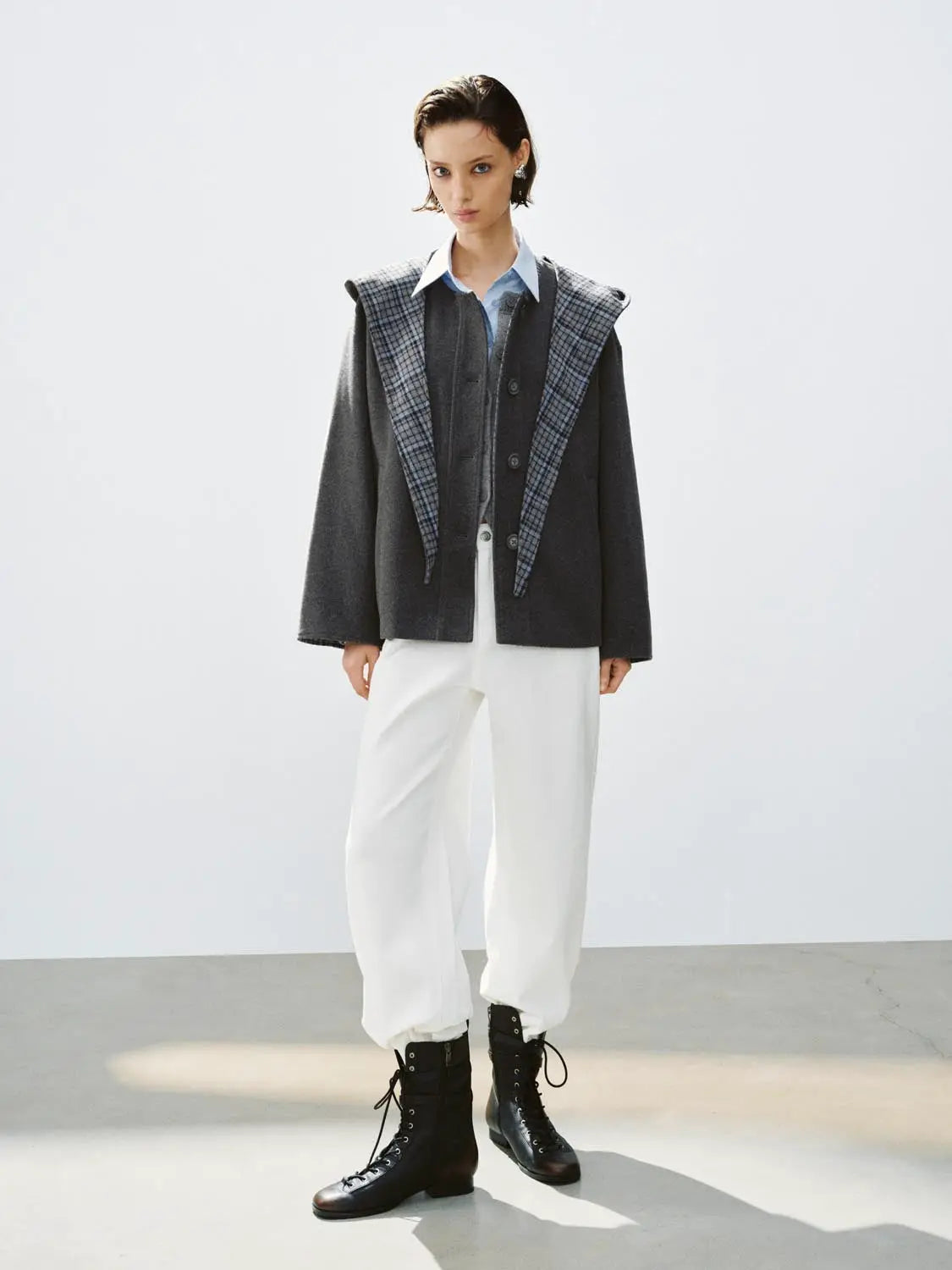 Coat with dark gray body and blue plaid draped lapels over a light shirt.