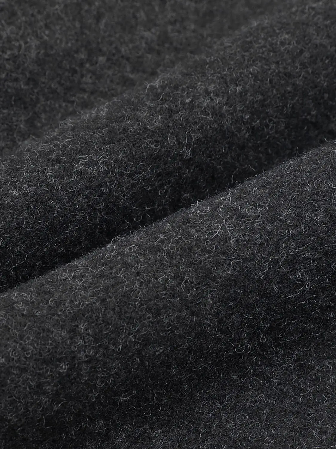 Coat fabric close-up in black wool boucle texture detail