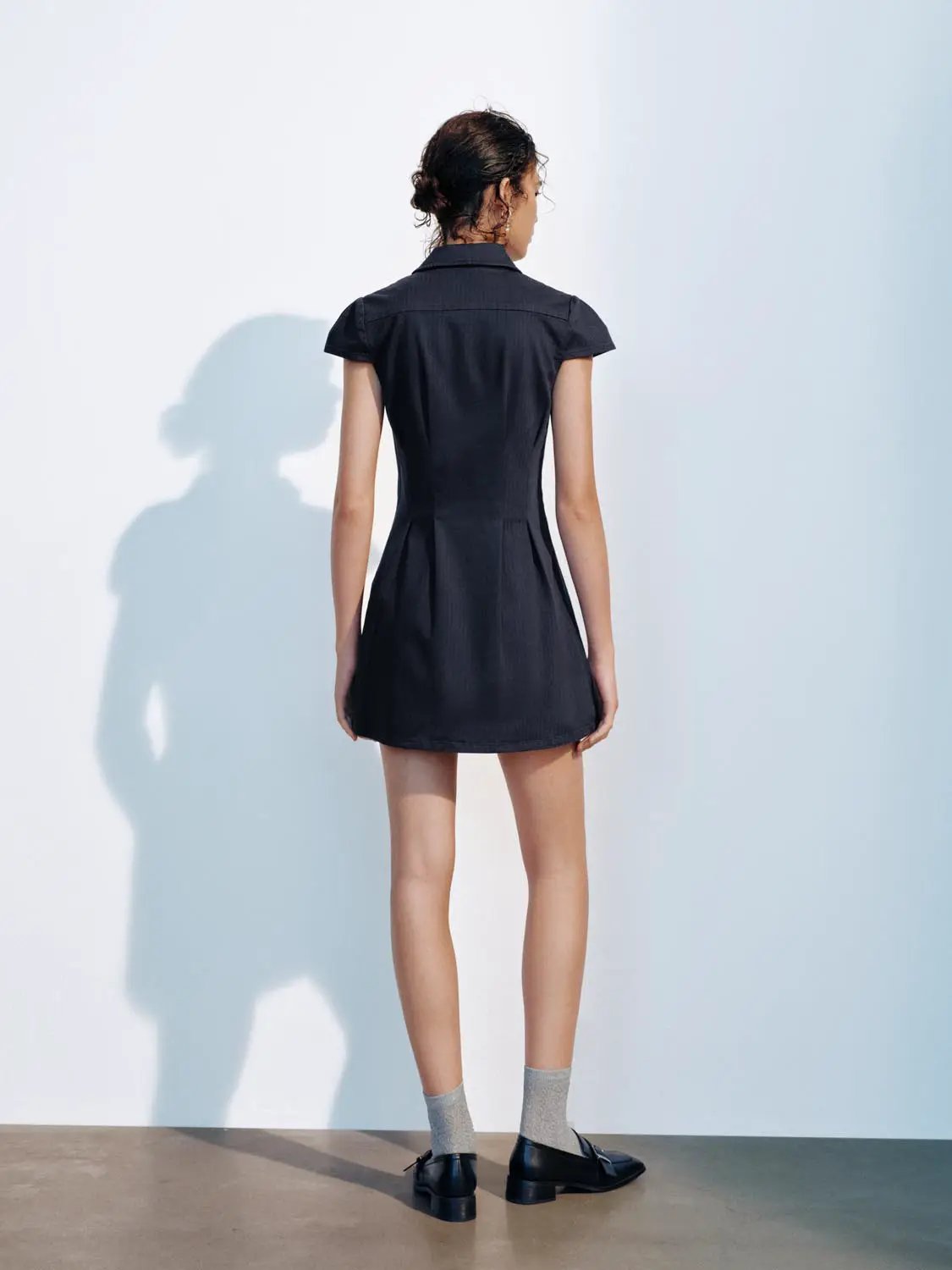 A-Line Dress in navy on model, back view with short puff sleeves and pleated skirt.