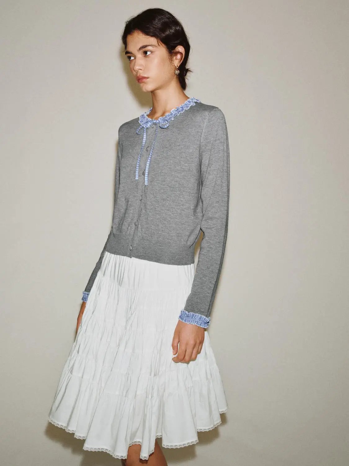 Knitted cardigan in heather gray with blue ruffle collar and cuffs, front button closure.