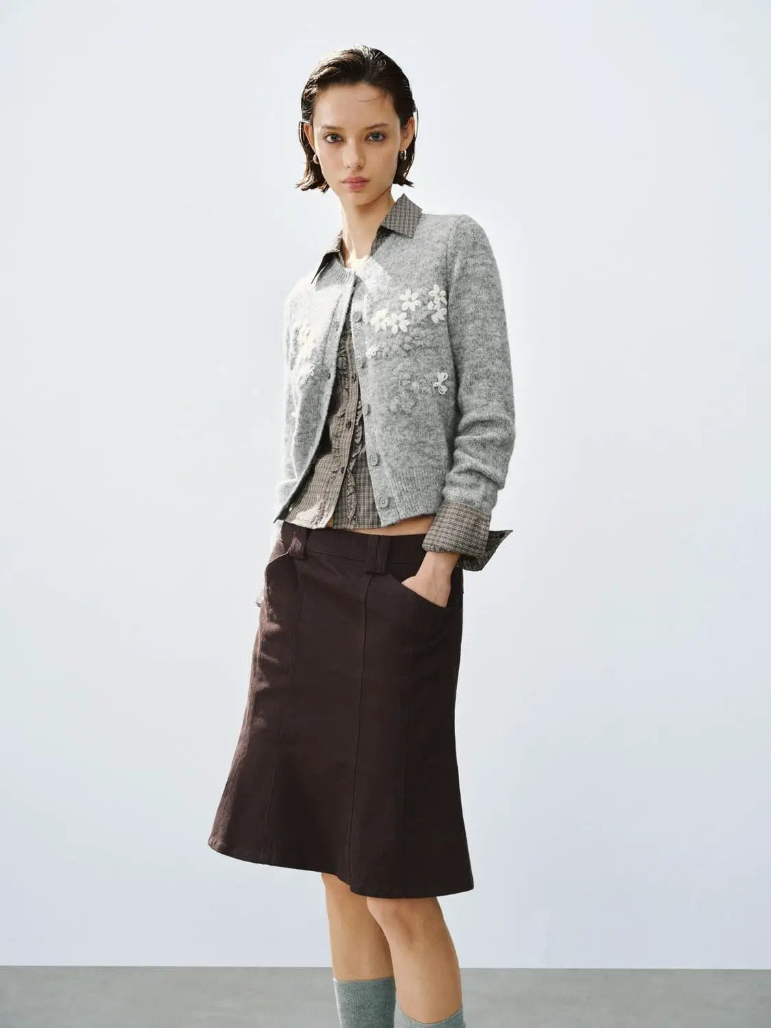Floral embroidered cardigan; grey knitted with white motifs, crew-neck long sleeve, over plaid shirt and dark skirt