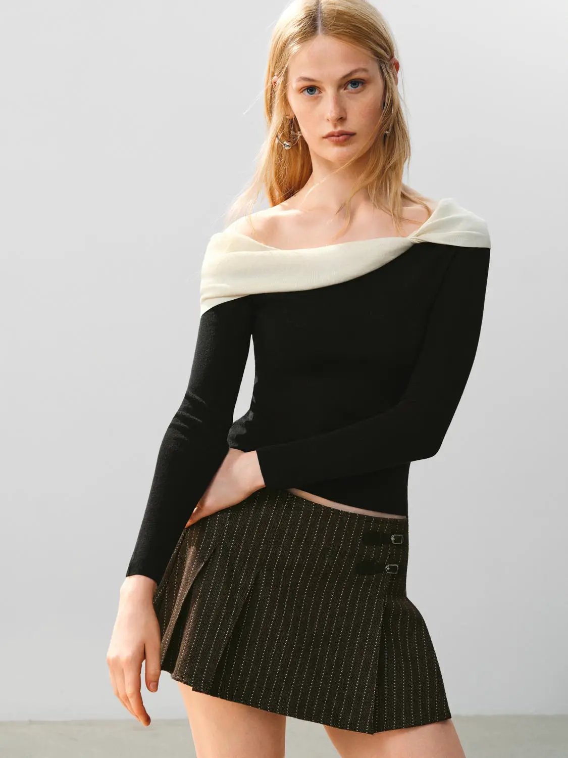 Knitted T-Shirts black long-sleeve top with ivory off-shoulder neckline.