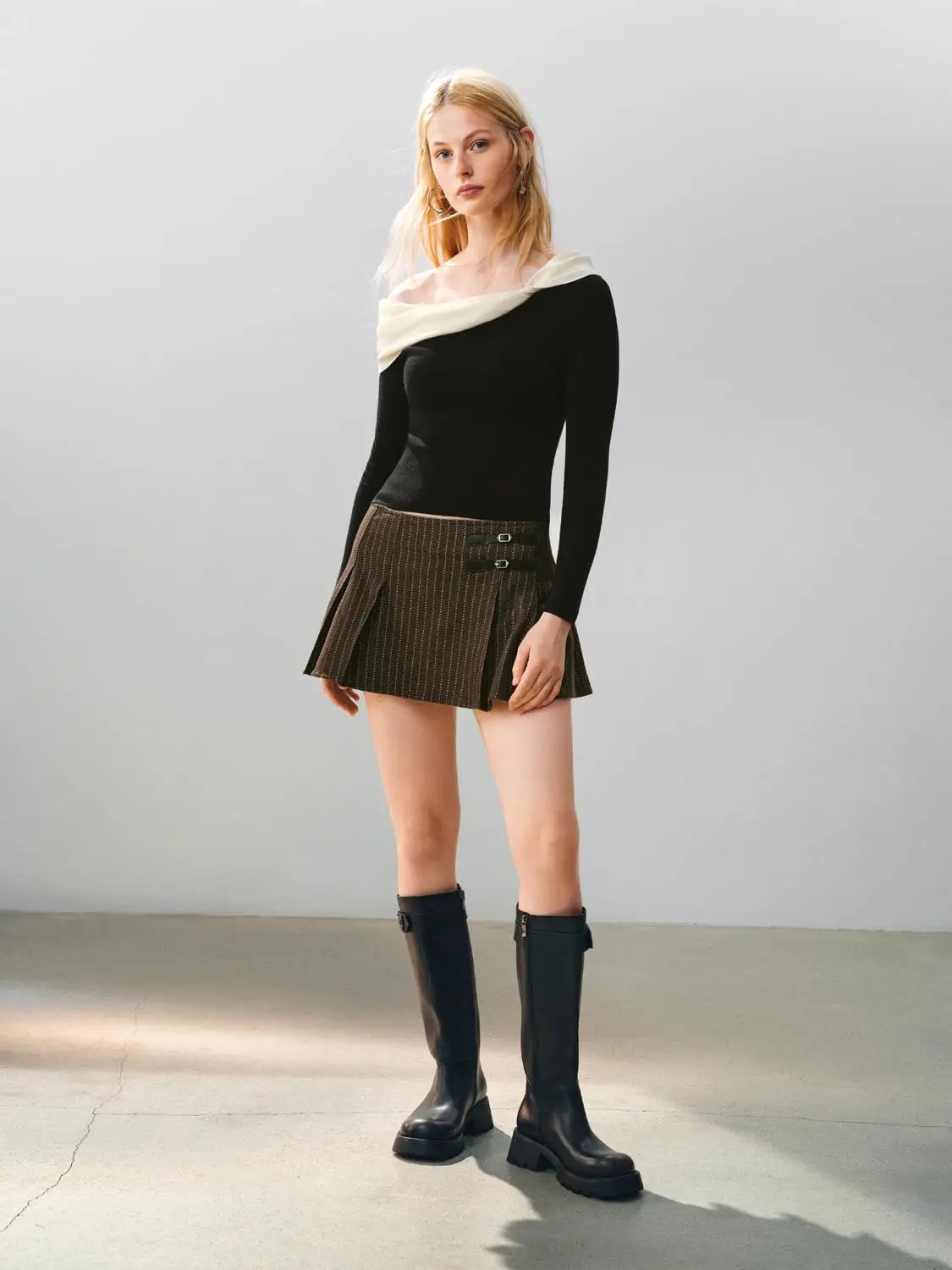 Knit T-Shirts: black long-sleeve knit top with ivory off-shoulder neckline; brown pinstripe mini skirt with buckles
