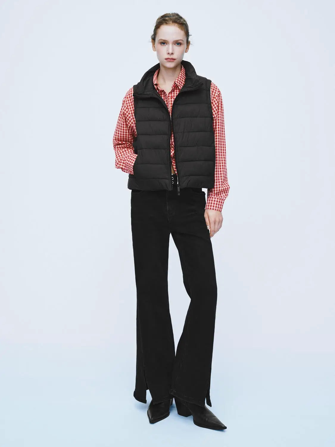 Padded jacket black puffer vest worn over red gingham shirt with black wide-leg pants