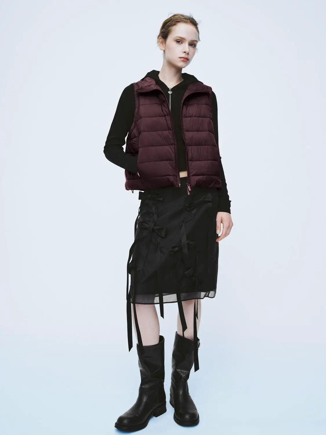 Padded jacket in burgundy, quilted puffer style worn over a black long-sleeve top.