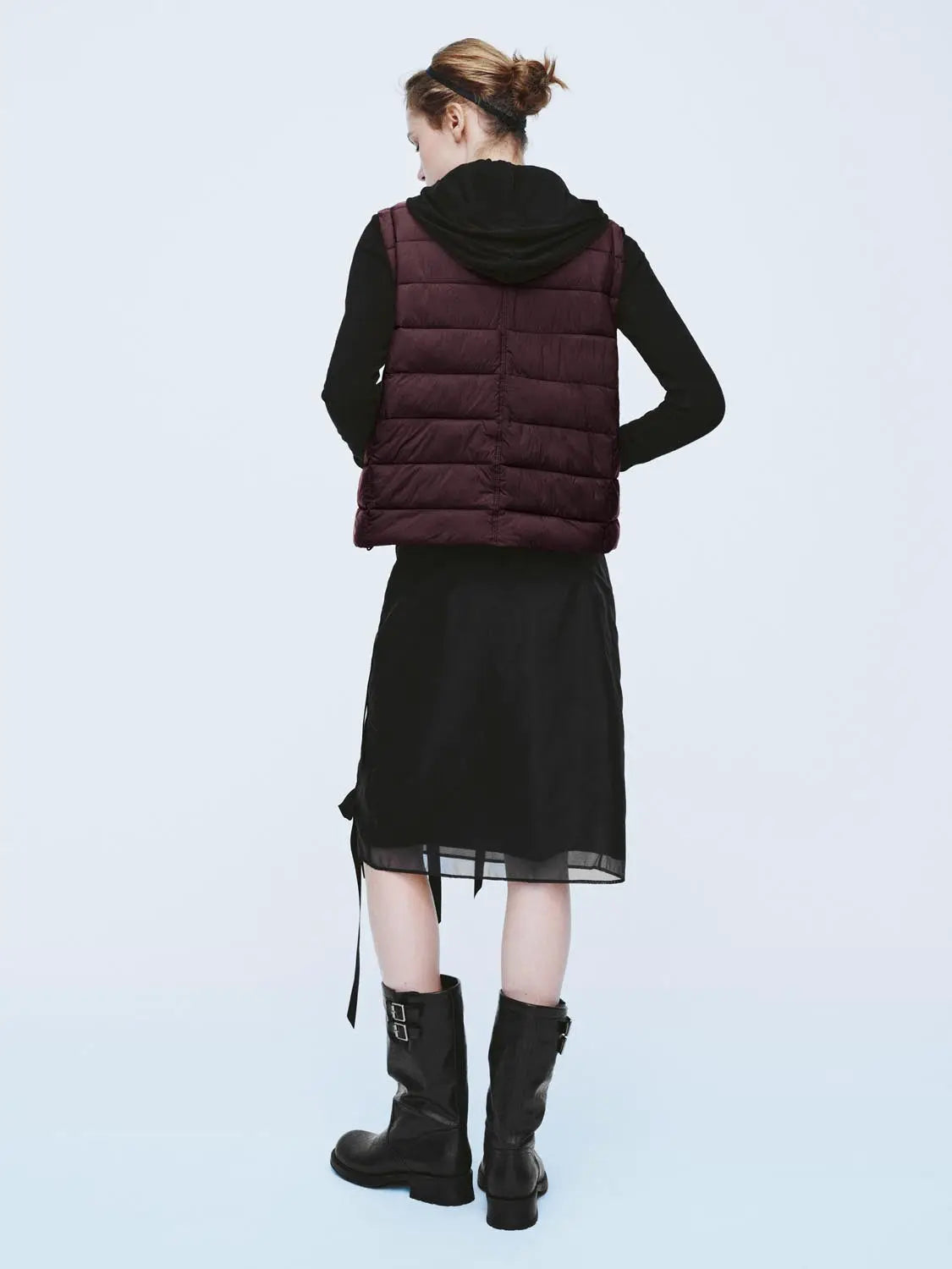 Padded jacket in burgundy quilted finish, seen from back on a model wearing black outfit