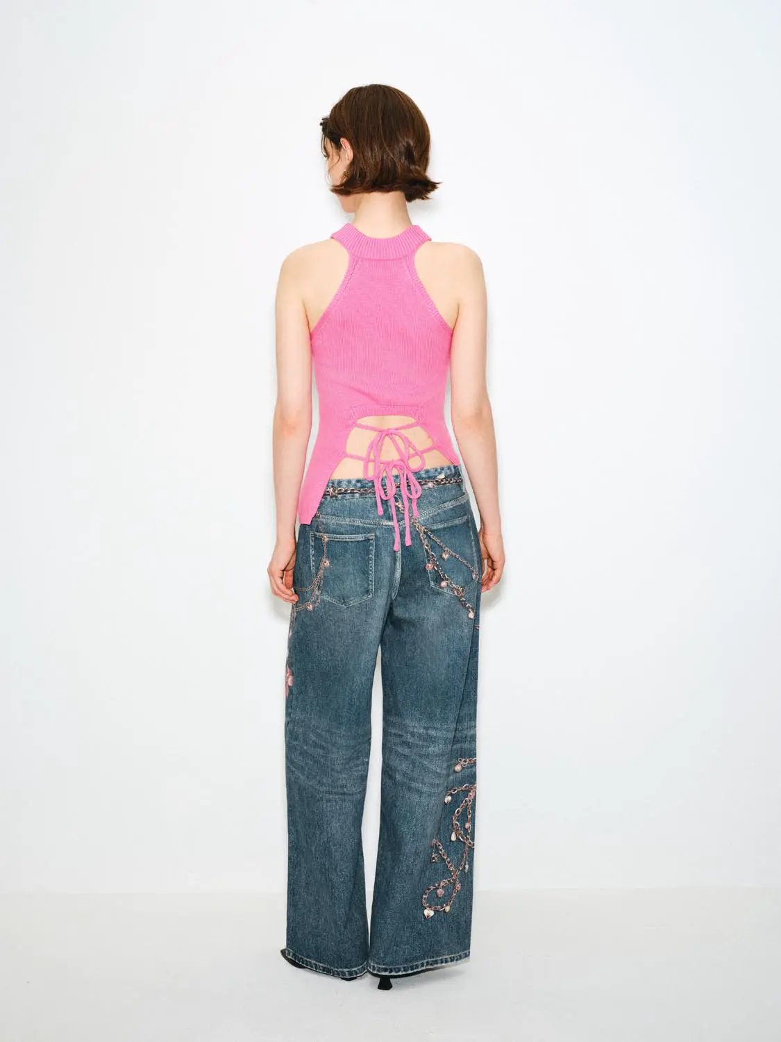 Knit T-Shirt pink halter-back top with lace-up, paired with wide-leg chain-embellished denim jeans