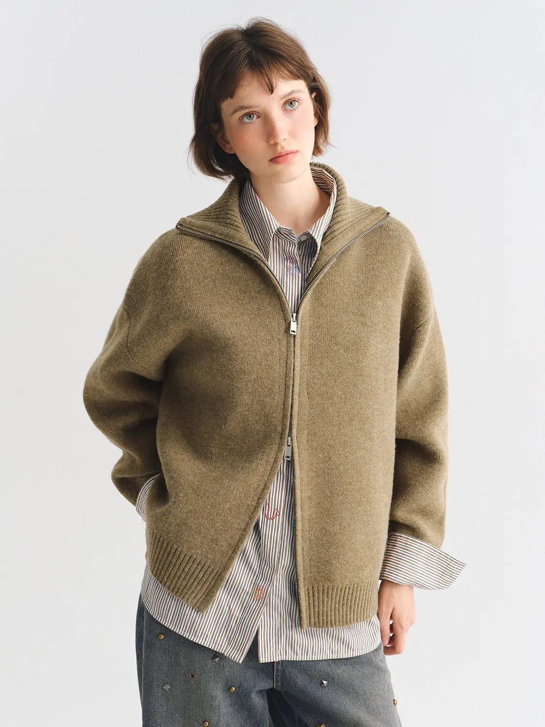 Knit jacket, tan knit with zip front, worn over striped shirt.