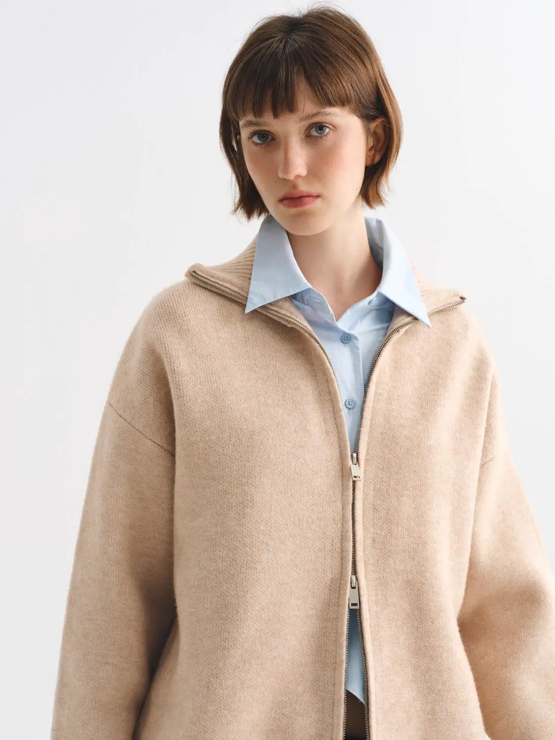 Knit jacket in beige, oversized, zip-front worn over a light blue shirt